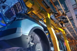 Bild zeigt moderne Automobilproduktion mit Maschinen und Arbeitern, symbolisiert Industrie-Wachstum und Innovation.