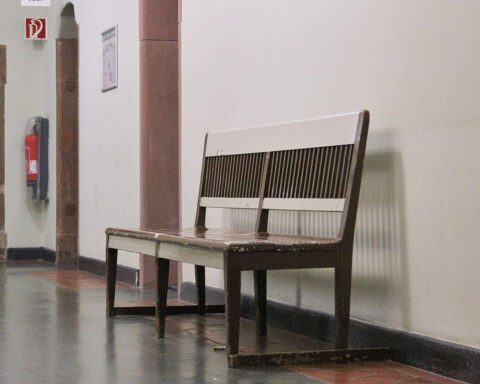 Sitzbank im Gericht, symbolisiert Personalmangel und lange Wartezeiten in der Justiz.