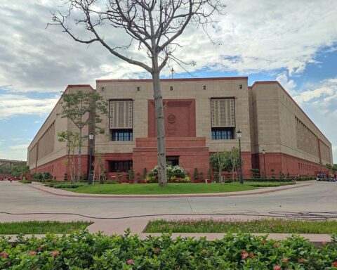 Indisches Parlament mit deutscher und indischer Flagge, symbolisiert diplomatische Beziehungen und politische Gespräche.