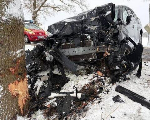 Ein beschädigtes Auto neben einem Baum, Winterbedingungen, Rettungskräfte vor Ort.