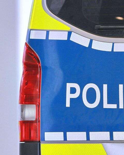 Polizeiinspektor überwacht Silvesternacht, Einsatzleiter mit Einsatzwagen, hektische, aber friedliche Atmosphäre trotz Vorfälle.