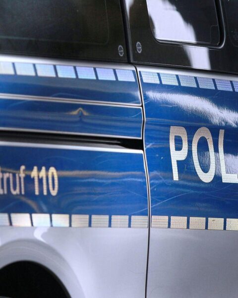 Ein Polizeieinsatzort im Wald, umgeben von Ermittlern und Absperrband, deutet auf einen Leichenfund hin.