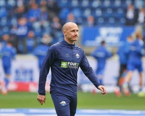 Sven Michel lächelt im SCP07-Trikot, umgeben von Fans und Pokalen des Vereins.