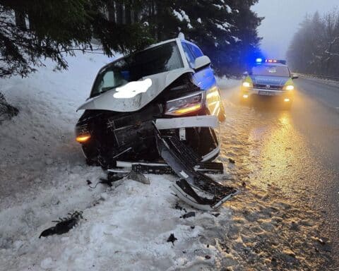 Verunfallter Transporter neben Baum, Polizei vor Ort, winterliche Straßenbedingungen erkennbar.
