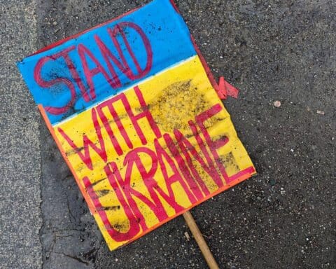 Schild "Stand with Ukraine" auf dem Boden, symbolisiert Unterstützung für die Ukraine im Konflikt.