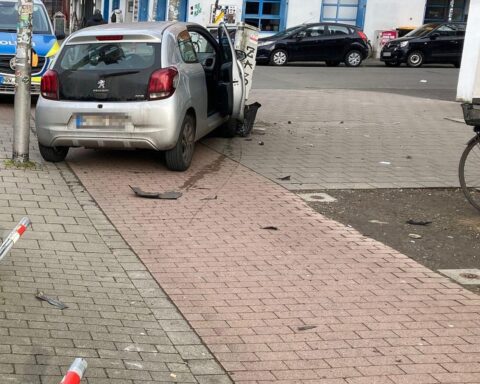 Autounfall in Münster: beschädigtes Auto, Poller, Telefonkasten, Polizei vor Ort, Warnung vor Drogen.