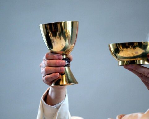 Ein katholischer Pfarrer, der während einer Messe mit Gläubigen in einer Kirche spricht.