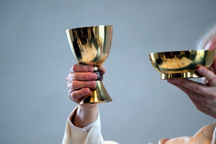 Ein katholischer Pfarrer, der während einer Messe mit Gläubigen in einer Kirche spricht.