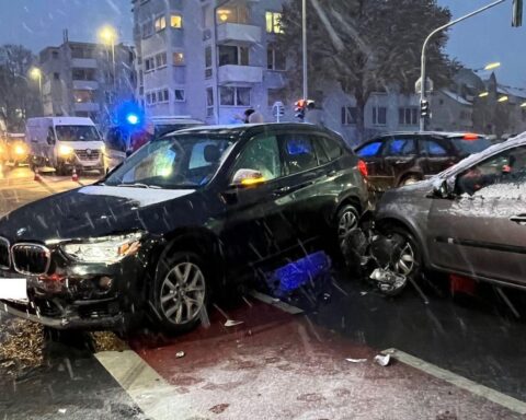 Unfallstelle mit zwei beschädigten Autos, Polizei vor Ort, leichte Verletzungen einer Beifahrerin.