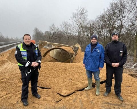 Sprengung einer Fliegerbombe: Einsatzkräfte am Ort des Geschehens, Autobahn im Hintergrund.