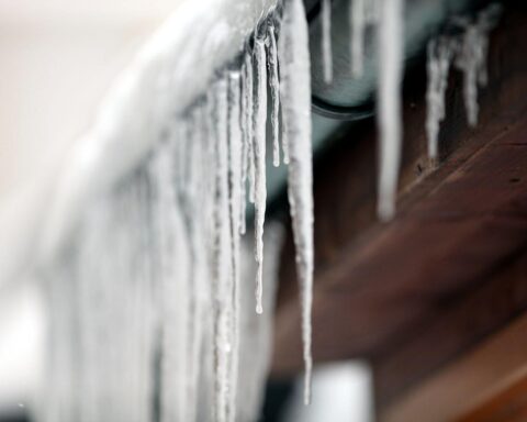 Eiszapfen hängen von einer Regenrinne, symbolisieren den strengen Frost in Bayern.