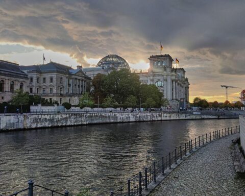Sonnenuntergang über dem Reichstagsgebäude, symboldhaft für Berlins kaltes, bewölktes Wetter.