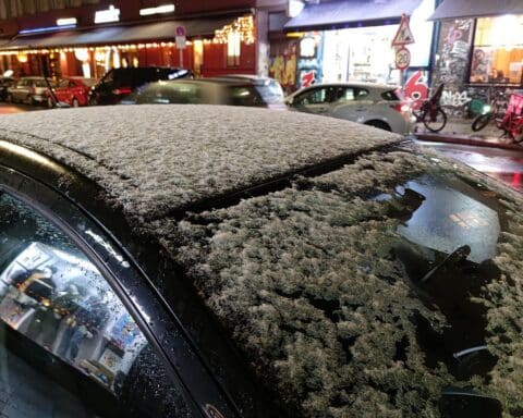 Schneebedecktes Autodach bei winterlichem Wetter, symbolisiert den stürmischen Tag in Nordrhein-Westfalen.