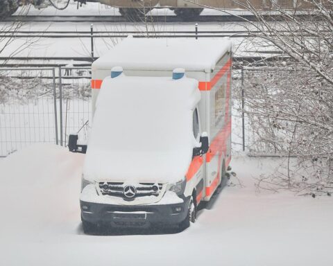 Rettungswagen im Schnee, winterliches Wetter mit Frost und dichten Wolken, sicherheitsrelevant.