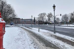 Schneebedeckte Straßen in Berlin mit warnenden Verkehrsschildern vor Glatteis und winterlichen Bedingungen.