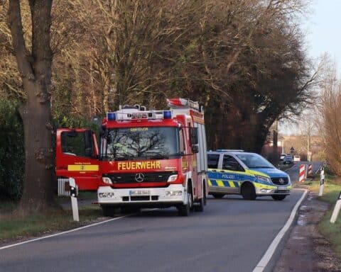 Zwei verletzte Motorradfahrer nach Zusammenstoß auf der Straße, Feuerwehr sichert Unfallstelle.
