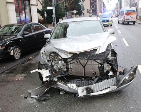 Zwei beschädigte Autos nach Kreuzungsunfall, rettende Einsatzkräfte und verletzte Personen vor Ort.