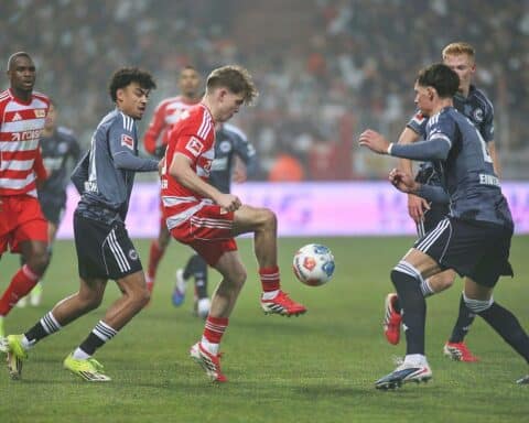 Spielszene mit Spielern von Union Berlin und Eintracht Frankfurt, intensiver Wettkampf, Fan-Emotionen.