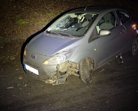 Eine beschädigte Autofahrerin neben ihrem Wagen nach einem Unfall in Reichshof.
