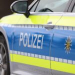 Polizeiauto an Unfallstelle mit Pkw und Lkw, Einsatzkräfte sichern die Umgebung ab.