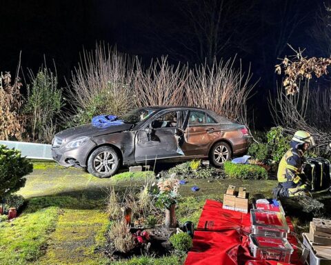 Ein Auto auf einem Friedhof, Rettungskräfte befreien Fahrer aus Fahrzeug nach Unfall.
