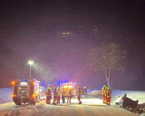 Ein Unfallauto auf dem Dach im Straßengraben, umgeben von schneebedeckter Fahrbahn.