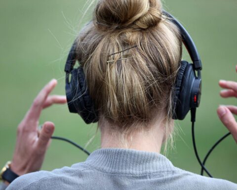Frau mit Kopfhörern, die Musik hört und Bad Bunnys Erfolge feiert.