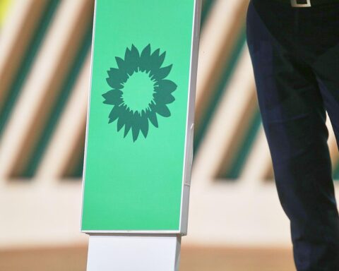 Grünen-Logo vor Berliner Silhouette, symbolisiert Fortschritt, Klimaschutz und soziale Gerechtigkeit.