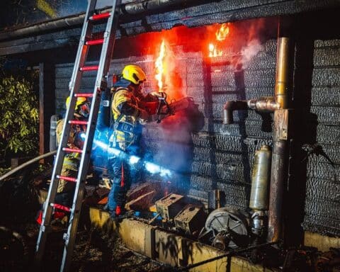 Vollbrand einer Saunahütte, Feuerwehr im Einsatz, Flammen und Rauch sichtbar, hilfreiche Eindämmung.