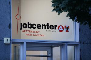 Jobcenter mit Wartenden, Symbol für Arbeitspflicht und Debatte über Bürgergeld-Empfänger in Deutschland.
