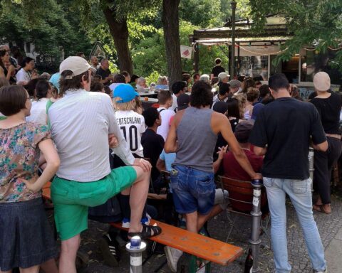 Menschen genießen Fußball-Weltmeisterschaft beim Public Viewing in einer fröhlichen, belebten Umgebung.