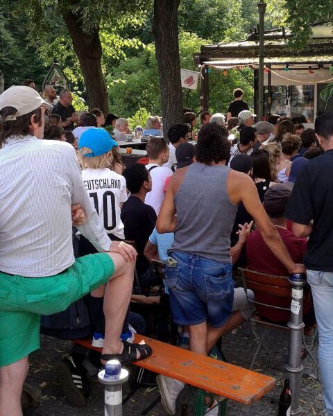 Menschen genießen Fußball-Weltmeisterschaft beim Public Viewing in einer fröhlichen, belebten Umgebung.