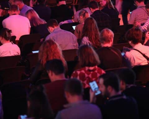 Junge Menschen nutzen Smartphones, symbolisieren digitale Herausforderungen und den Bedarf an Schutzmaßnahmen.