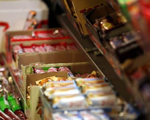 Vielfältige Süßigkeiten in bunten Verpackungen, die den Zuckerkonsum symbolisieren und Diskussionen entfachen.