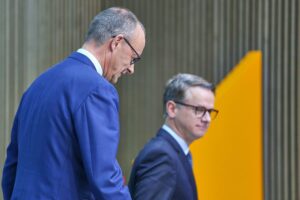 Friedrich Merz und Carsten Linnemann lächeln zusammen bei einer politischen Veranstaltung in Berlin.