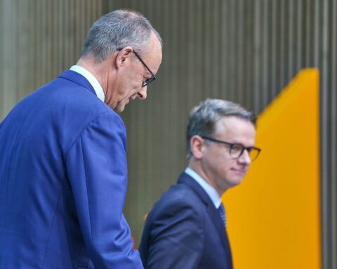 Friedrich Merz und Carsten Linnemann lächeln zusammen bei einer politischen Veranstaltung in Berlin.