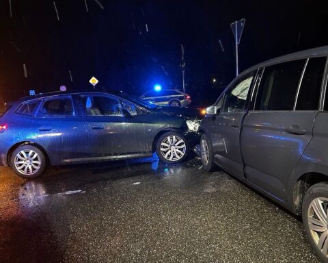 Zwei beschädigte Autos nach einem Unfall, Polizei und Rettungswagen in der Nähe.