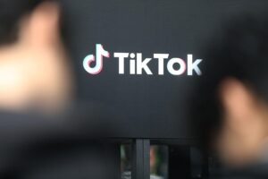 Tiktok-Logo vor Brüsseler Hintergrund, symbolisiert Prüfung des süchtig machenden Designs der App.
