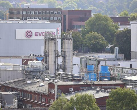 Evonik-Logo vor einem Hintergrund aus Chemie- und Industrieelementen im Kontext des US-Zollstreits.