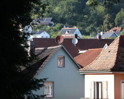 Bild mit glücklichen Familien vor ihren neuen Häusern, symbolisiert Förderung beim Immobilienkauf.