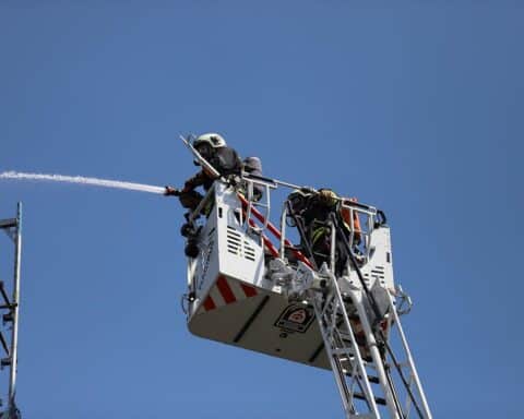 Feuerwehrleute bei Einsätzen, mit Feuerwehrfahrzeug, Feuerwehrhaus im Hintergrund, aktive Gemeinschaft.