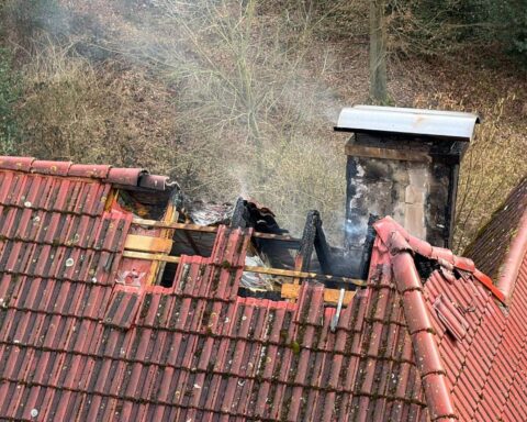 Dachstuhlbrand, Feuerwehr im Einsatz, Rauchentwicklung, Löschfahrzeuge, Einsatzkräfte bekämpfen Feuer.