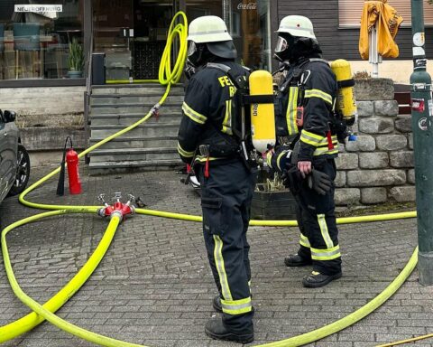 Feuerwehrleute löschen Brand in Lüftungsanlage während Karnevalszug, Einsatzkräfte rücken schnell an.