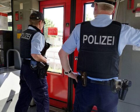 Zwei Polizisten im Zug überwachen die Sicherheit während einer Diskussion über erhöhte Präsenz.