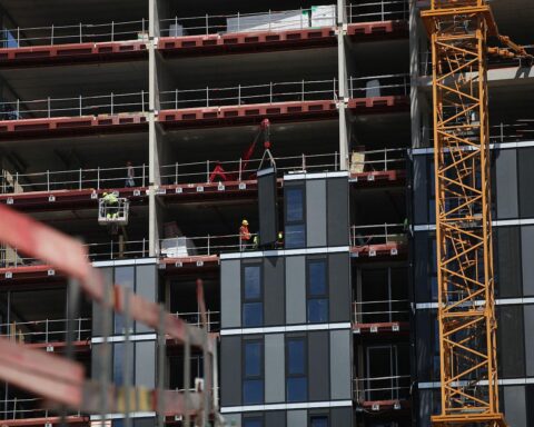 Baustelle mit Bauarbeitern und Materialien, symbolisiert den aktuellen Zustand im deutschen Wohnungsbau.