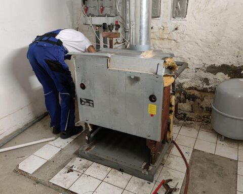 Ein Handwerker bei der Renovierung einer Gasheizung, symbolisiert Energiewende und gesetzliche Herausforderungen.