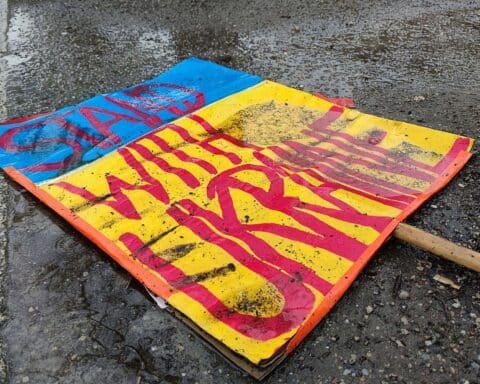 Schild mit "Stand with Ukraine" auf dem Boden, symbolisiert Solidarität und Unterstützung für die Ukraine.