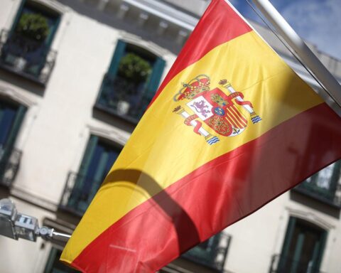 Spanische Fahne vor dramatischem Wetterhintergrund, symbolisiert Auswirkungen von Sturmtiefs und Hochwasser.