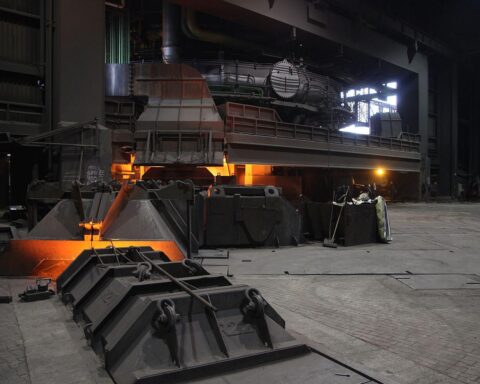 Symbolisches Bild: Stahlproduktion mit Arbeiter*innen und europäischen Flaggen, die lokale Wertschöpfung symbolisieren.