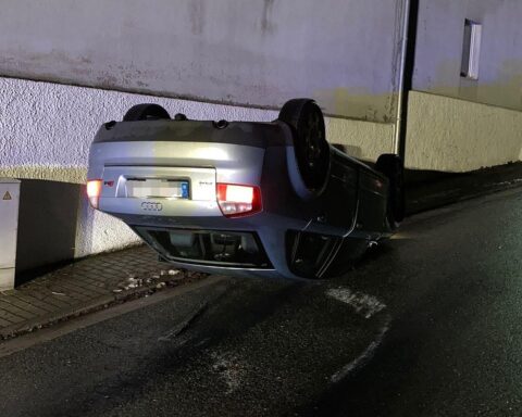 Unfallort mit umgekehrtem Auto, Polizei vor Ort, Ermittlungen zu flüchtigen Insassen.